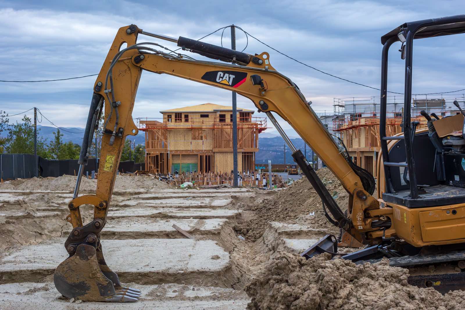 Excavator digging foundation trenches at a residential construction site