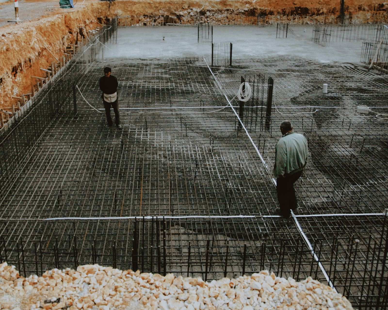 Excavated foundation with a steel reinforcement grid and pale limestone spoil