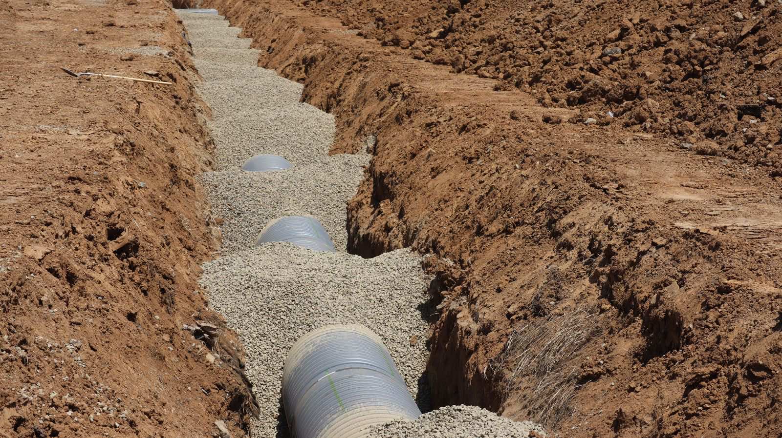 Corrugated drain pipe bedded in gravel in an open drainage trench