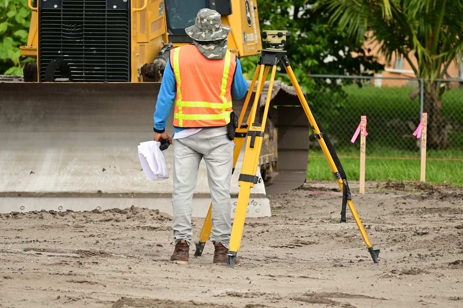 Surveyor taking elevation measurements with a tripod-mounted level
